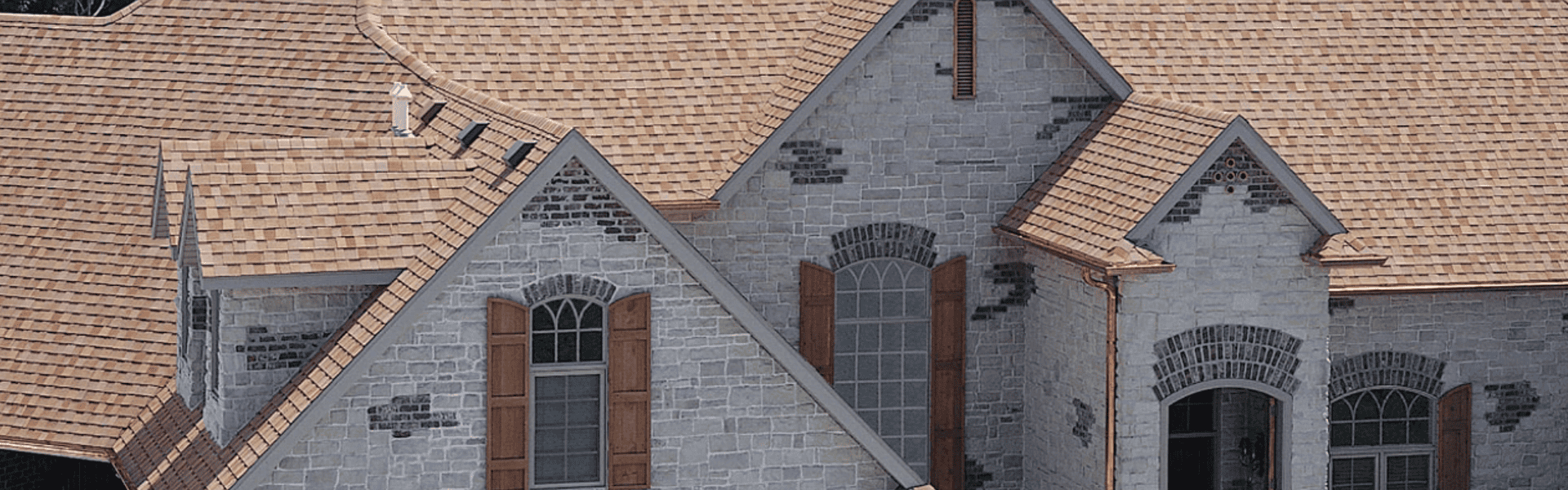 Stone and shingle home with brown roof representing quality residential roofing in Western Colorado