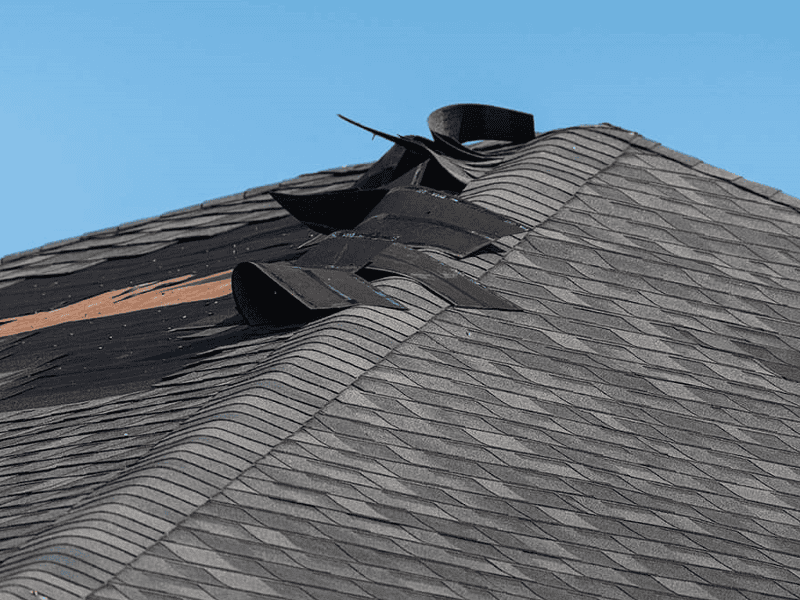 Asphalt shingle roof with storm damage and missing shingles